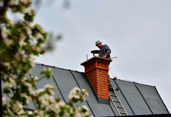 Mason working at a brick chimney on a Brooklyn metal roof