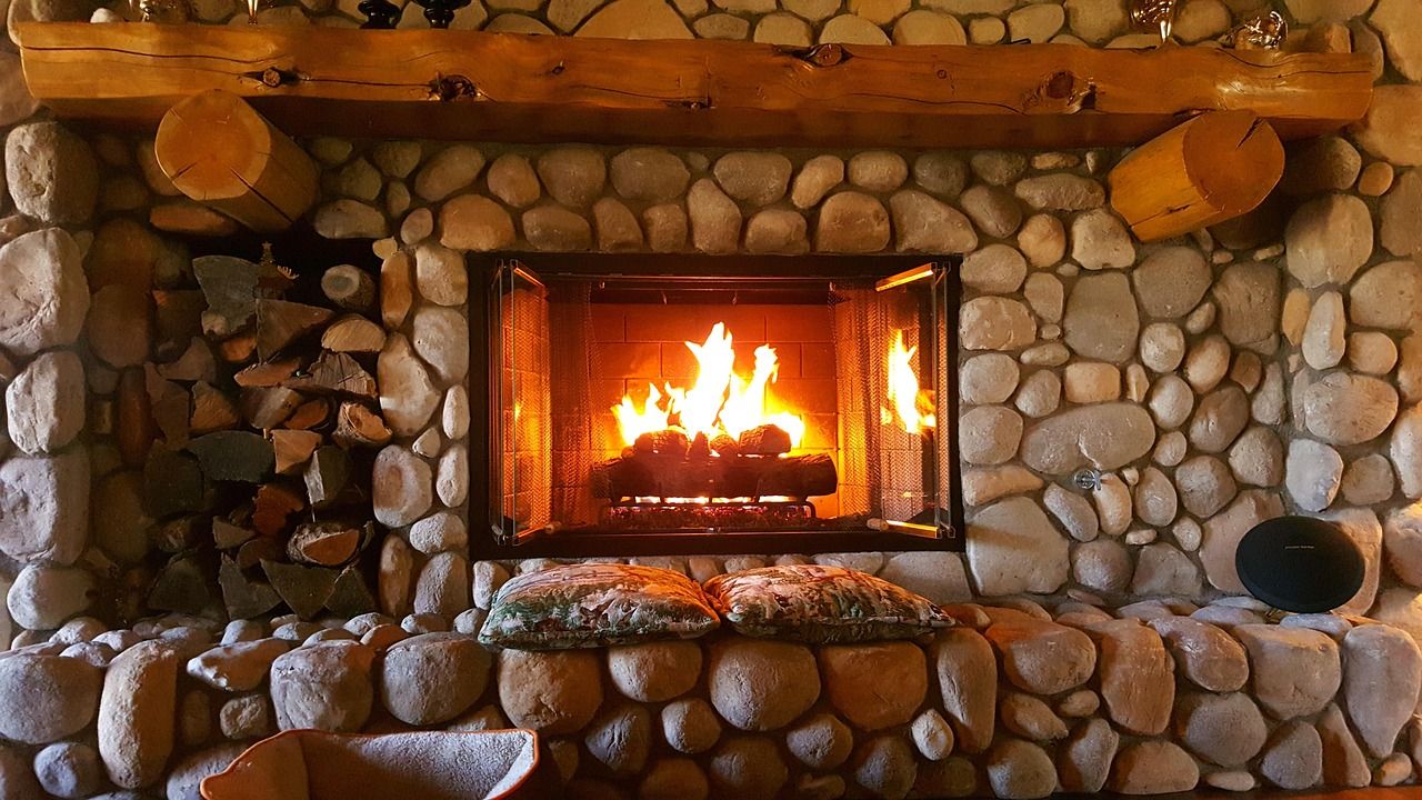 Restored stone fireplace with a timber mantel and burning fire